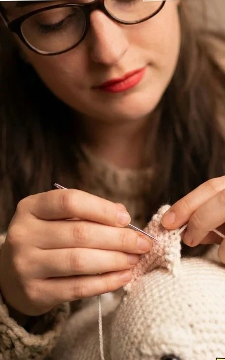 Ing. Jessy Pusch näht an einem handgestrickten Kuscheltier