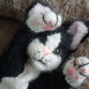 Handgestrickte schwarz-weiße Katze liegt im Körbchen