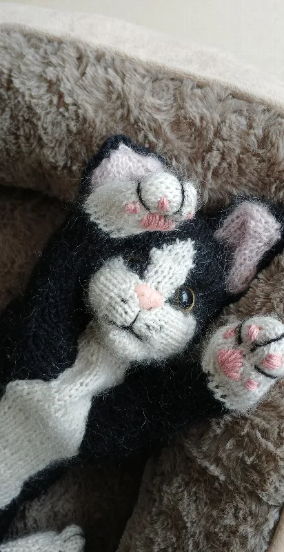 Handgestrickte schwarz-weiße Katze liegt im Körbchen